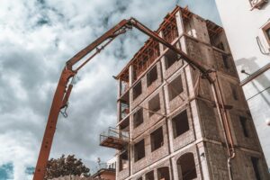 Concrete pump truck delivering mixture to the building under construction